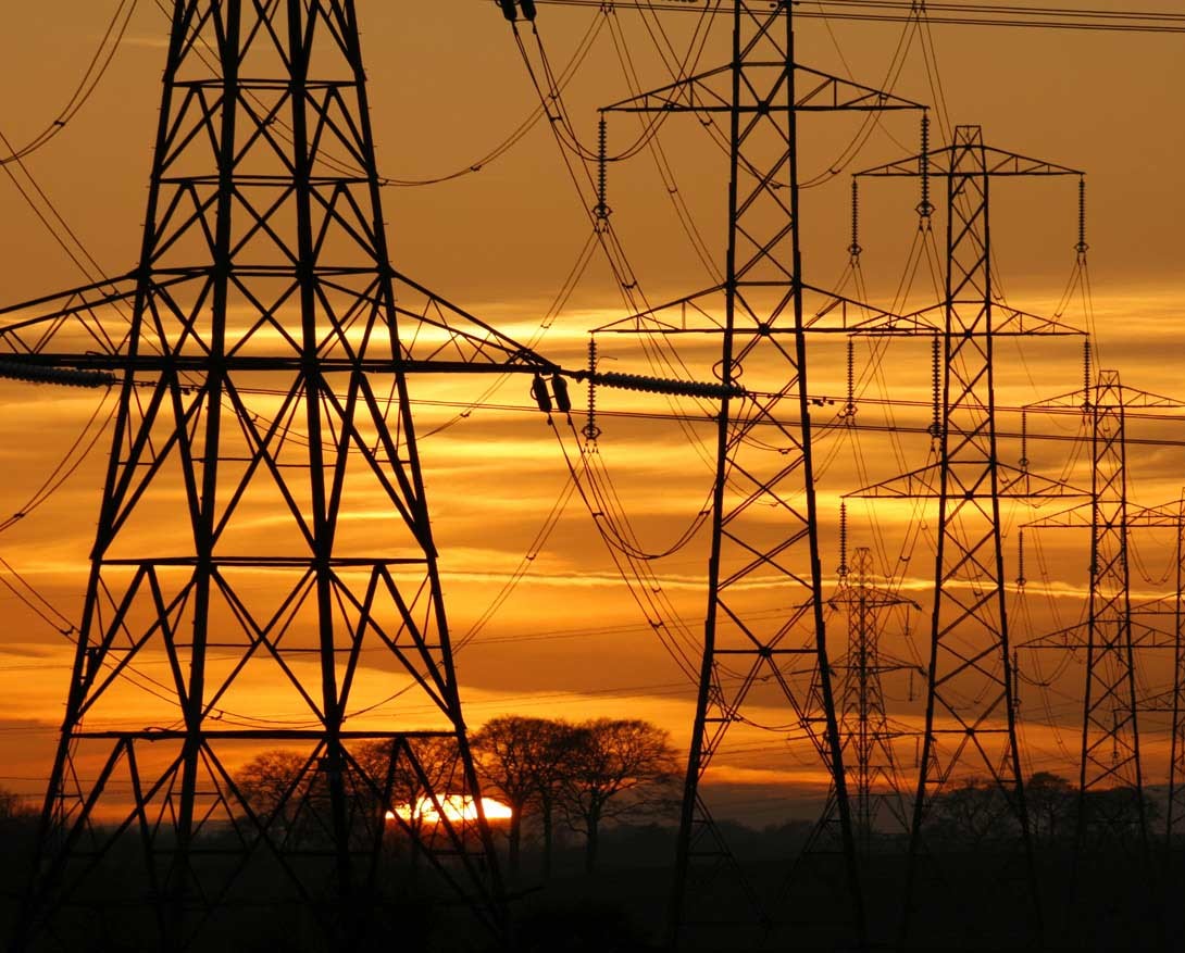 Sun setting behind a row of electricity pylons